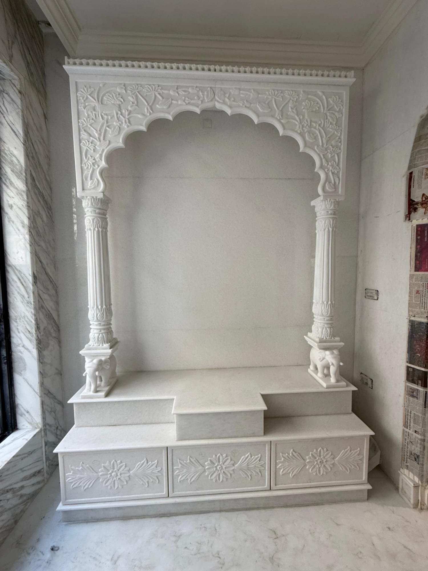 Custom white marble mandir with carved arch, pillars and elephant plinths